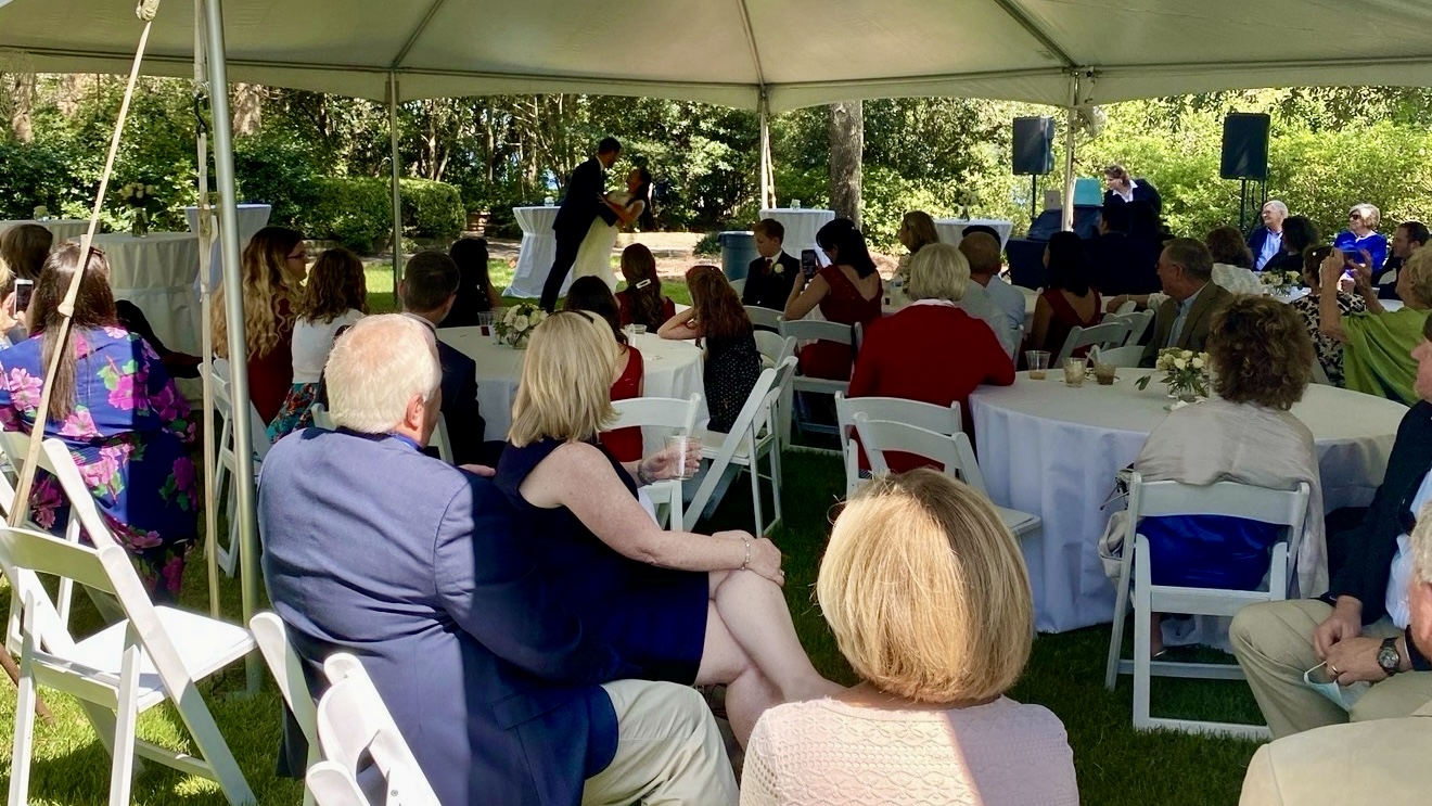 Guests seated beneath a tent at an outdoor celebration