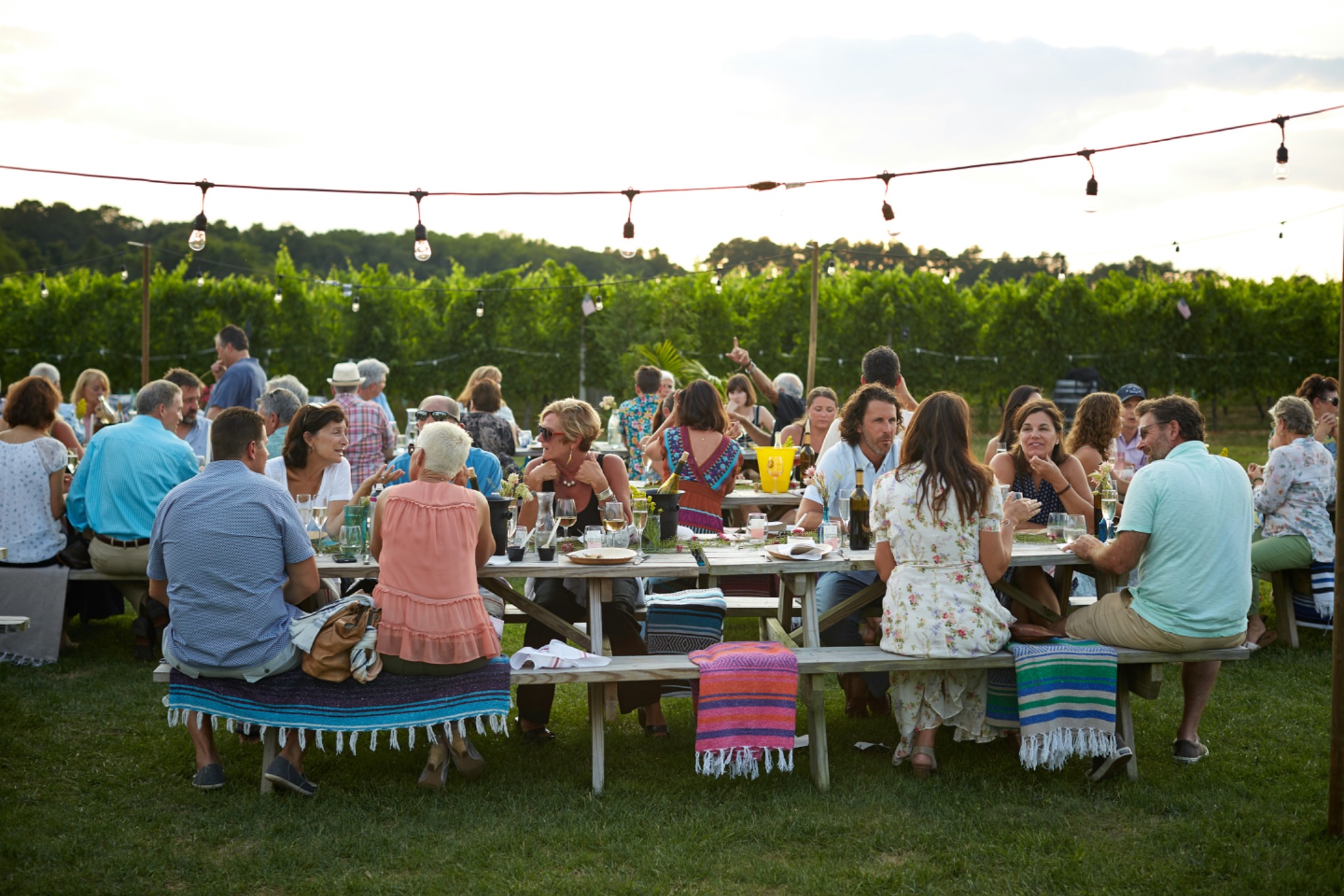 Guests gathered around long outdoor tables beneath string lights